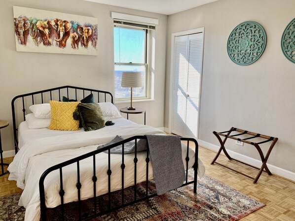 Restful retreat with a black metal bed, patterned rug, and city view.