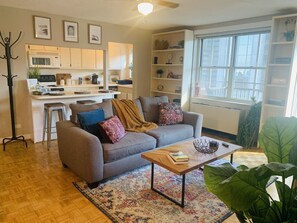 Relax in this stylish living space with a sofa, coffee table, and large plant, offering a view of the outside.