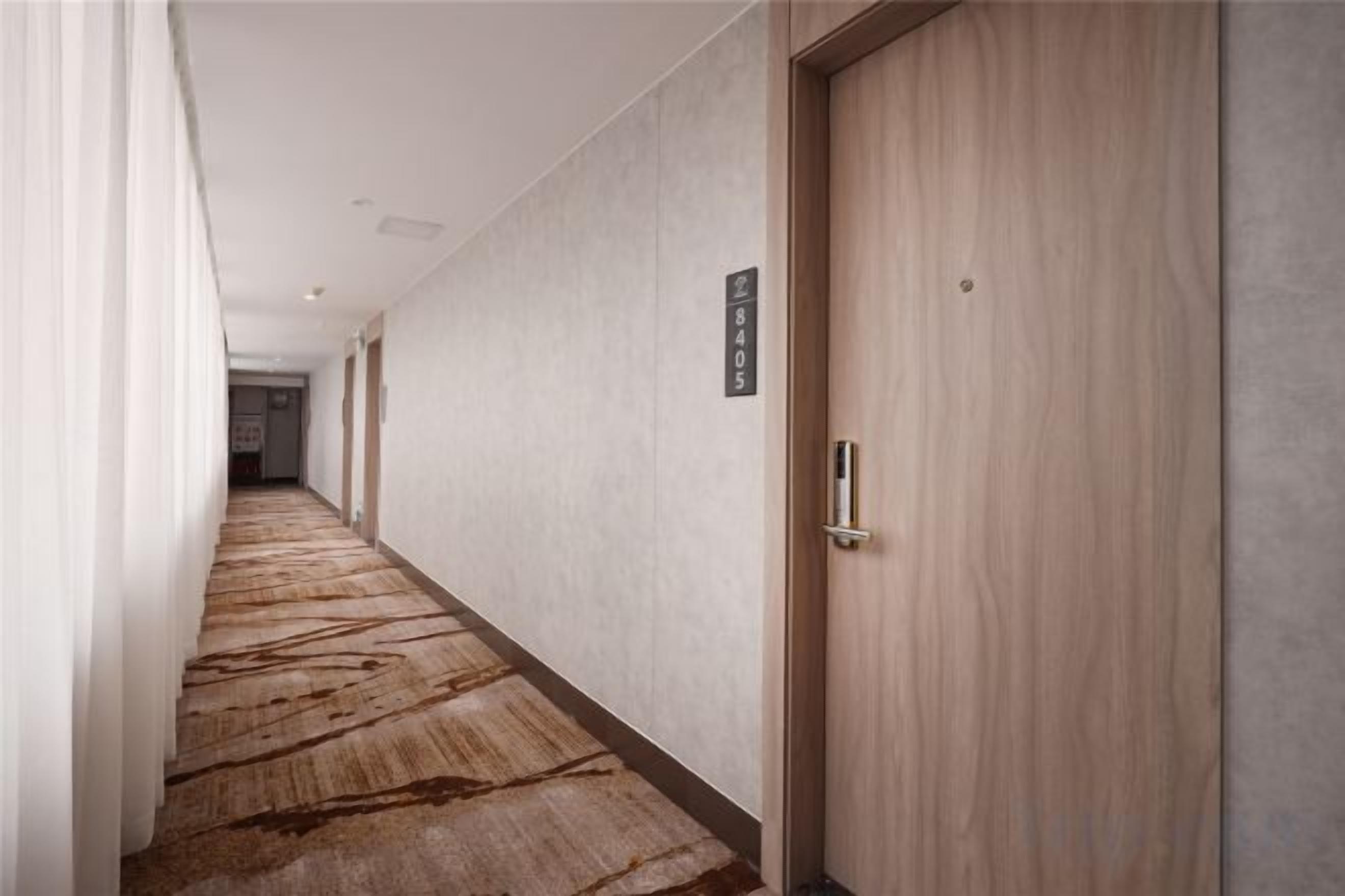 A hotel corridor with a carpeted floor, a wooden door, and a sign on the wall.
