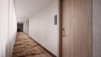 A hotel corridor with a carpeted floor, a wooden door, and a sign on the wall.