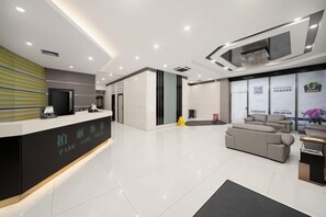 A modern reception area with a reception desk, a sofa, and a large window with a view. - Park Lane Hotel (Jiangmen Shuinan) (Jiangmen)