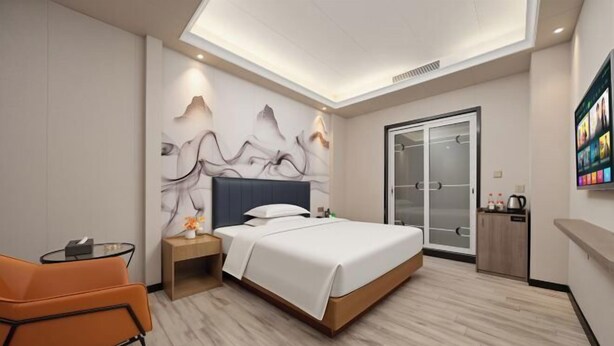A modern hotel room with a bed, nightstand, orange chair, and a glass door closet. - Park Lane Hotel (Jiangmen Shuinan) (Jiangmen)