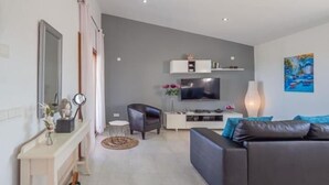 A modern living room with a grey sofa, a TV, and a painting on the wall. - El Rafal de Son Alberti Petitona (Buger)