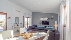 A modern living room with a sofa, TV, and a dining area with a table and chairs. - El Rafal de Son Alberti Petitona (Buger)