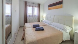 A hotel room with two beds, a large mirror, a painting on the wall, and a window with curtains. - El Rafal de Son Alberti Petitona (Buger)