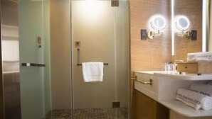 A hotel bathroom with a glass-enclosed shower, a vanity with a mirror, and a towel rack with a white towel. - James Joyce Coffetel (Changde)
