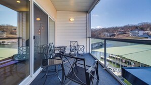 A balcony with a glass railing, a table, and chairs. - Water Views + Pool Access: Lake Ozark Escape! (Lake Ozark)