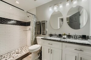 A modern bathroom with a shower, toilet, vanity with a sink, and two mirrors.