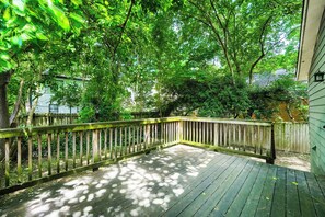 Un pontile in legno con ringhiera, circondato da alberi e una casa sullo sfondo.