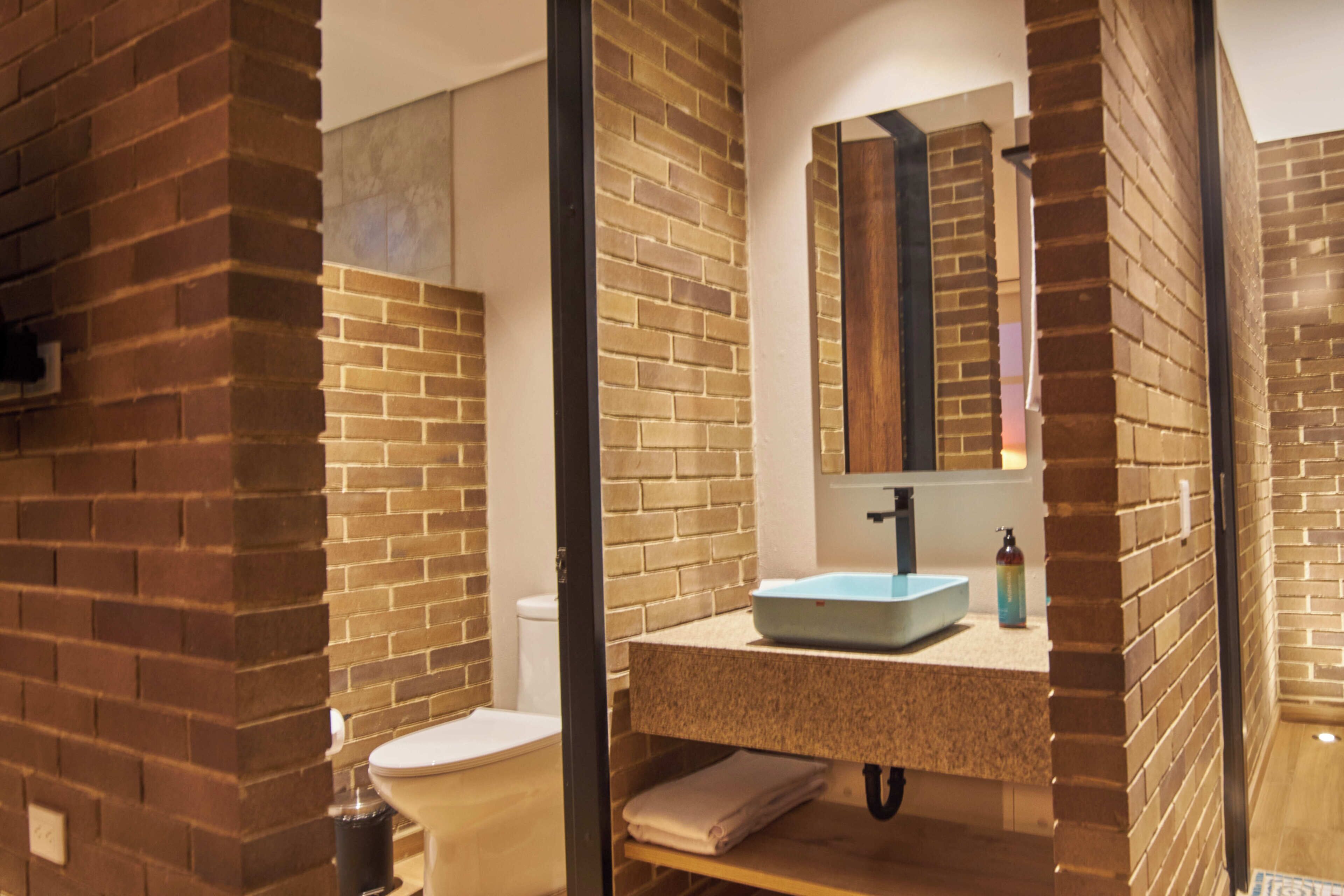 A bathroom with a visible toilet, a sink with a mirror above it, and a towel rack.