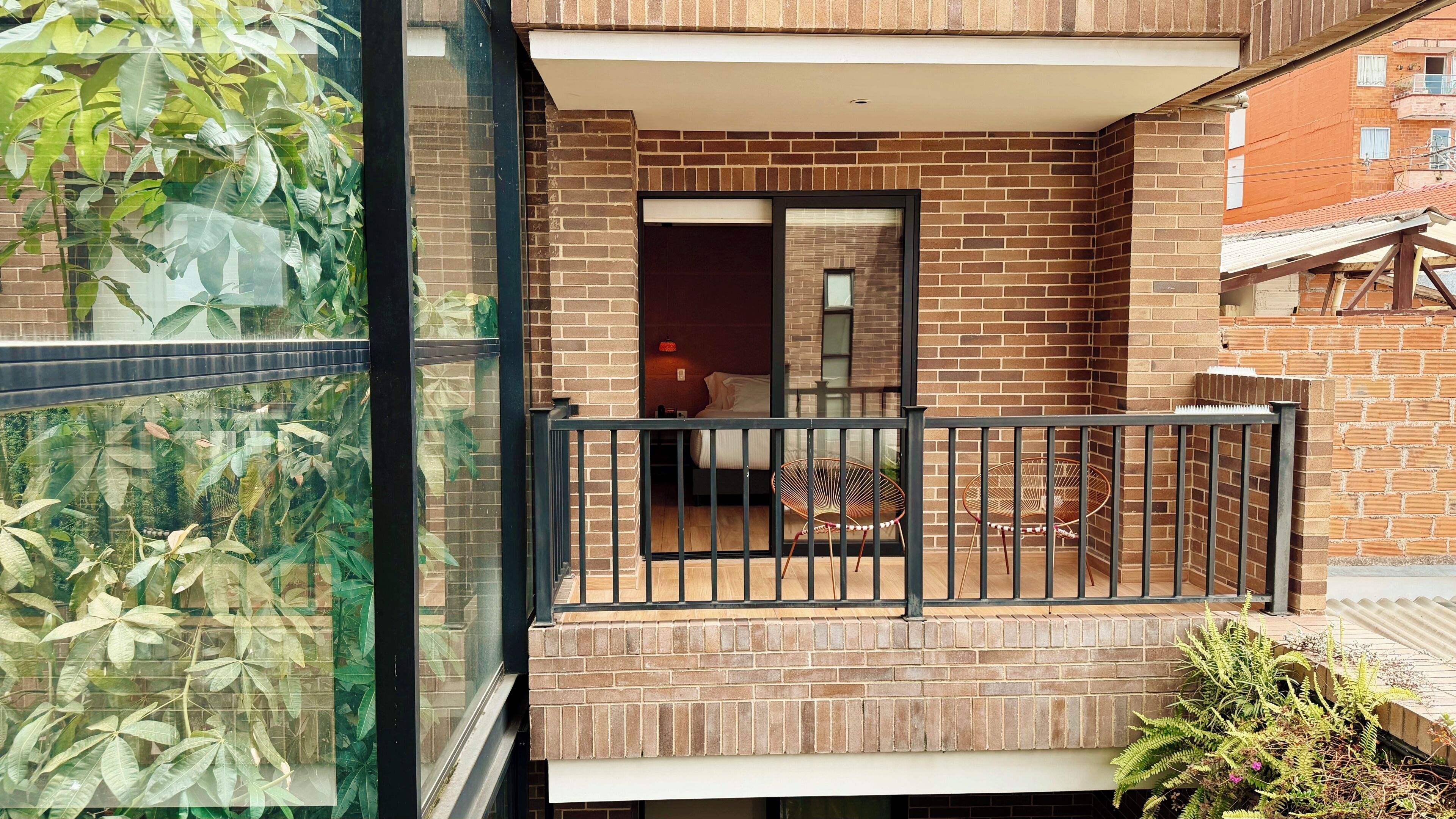 A modern apartment with a balcony, a bed, and a small seating area.
