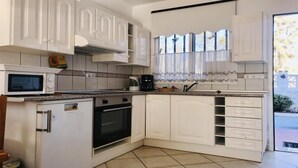 A compact kitchen with white cabinetry, a microwave, a coffee maker, and a built-in oven. - WIFI+and next to the beach and in the centre (Costa Calma (incl. Urbanización Cañada del Río))