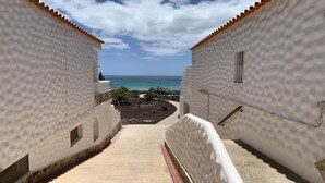 A pathway leading to a beach with white buildings and a clear sky. - WIFI+and next to the beach and in the centre (Costa Calma (incl. Urbanización Cañada del Río))