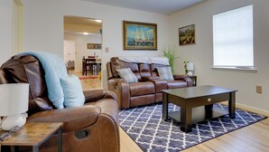 Ein Wohnzimmer mit einem braunen Ledersofa, einem passenden Sessel, einem Couchtisch und einem gemusterten Teppich.