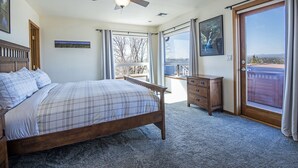 Un dormitorio con cama, cómoda, ventilador de techo y un ventanal con vistas.