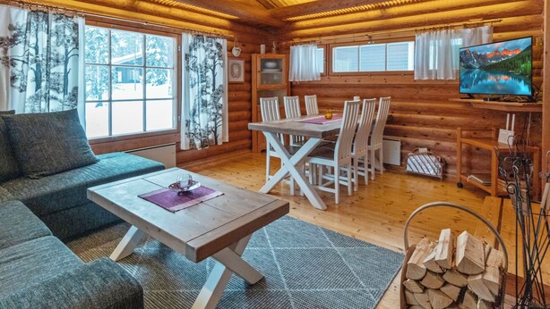 L’intérieur d’une cabane en rondins, avec un canapé, une table à manger, des chaises, un téléviseur et une cheminée.