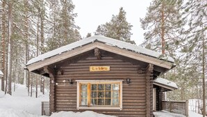 Une cabane en rondins avec une porte en bois et une enseigne sur laquelle on peut lire « Lakka ».