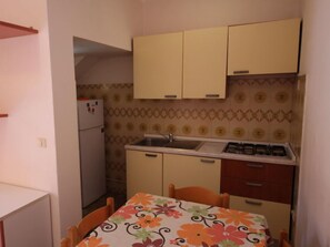 Una cocina compacta con estufa a gas, lavamanos y dos armarios.
