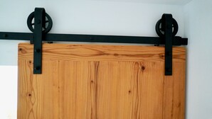 A wooden barn door with black metal hardware. - Three-room vacation apartment 2, approx. 63 sqm with balcony and wonderful view (Reit im Winkl)
