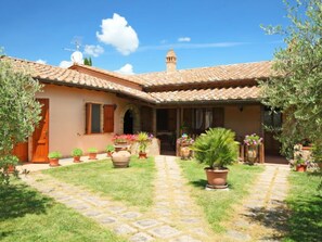 A traditional Mediterranean-style villa with a tiled roof, a central courtyard with potted plants, and a small tower-like structure.