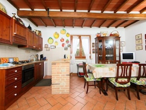 A kitchen with wooden cabinets, a brick island, and a dining area with a table and chairs.