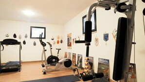 Un gimnasio con diverso equipo de ejercicio, una cinta de correr y carteles en la pared.