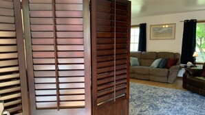 A room with a wooden partition, a sofa, and a rug. - View Peaceful Pond while lounging in this open studio apartment! (Warsaw)