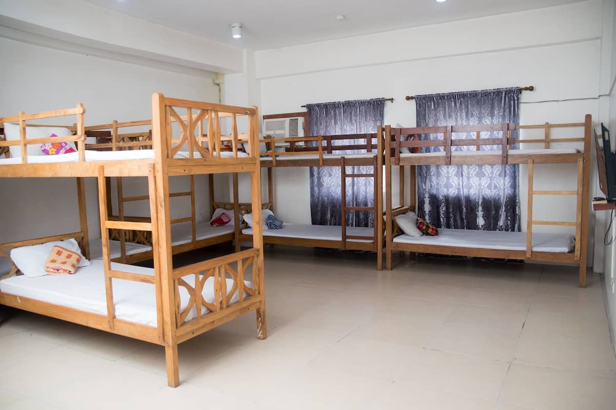 A room with bunk beds, a television, and curtains.