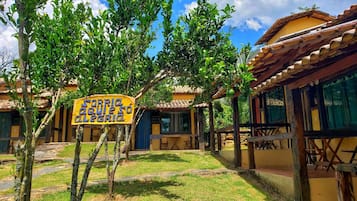 Un patio con un letrero que dice “SORRIA a todos a alegria”, rodeado de edificios con tejados de azulejos y estructuras de madera.
