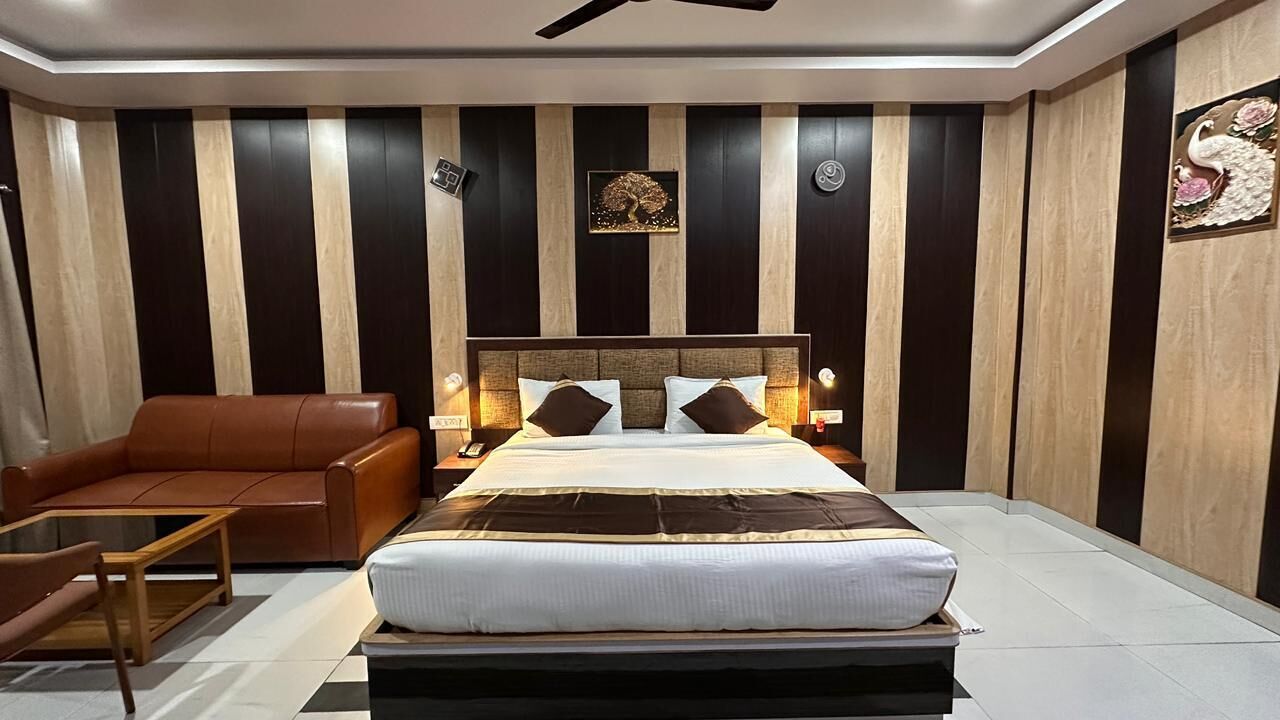Un dormitorio con una cama, un sofá de cuero marrón, una mesa de centro de madera y una mesita de noche con lámpara.