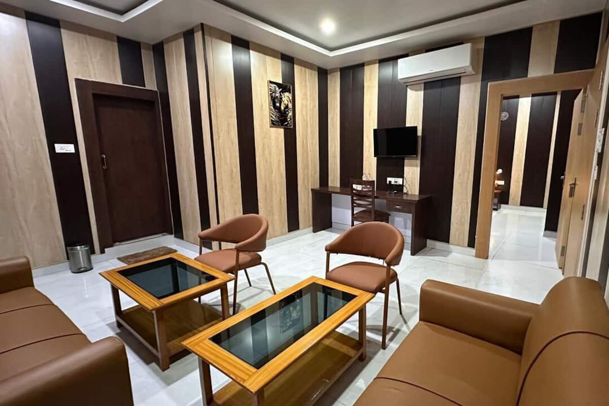 A modern living room with leather sofas, glass-top coffee tables, and a flat-screen TV mounted on the wall.