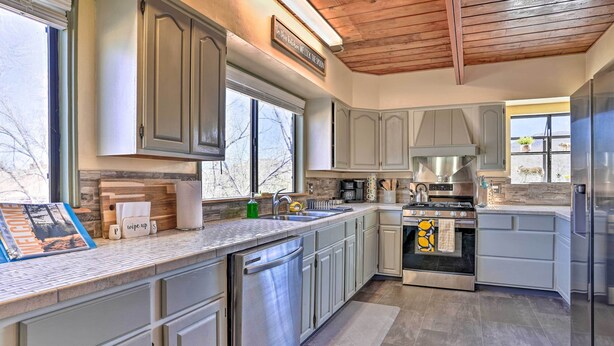 A modern kitchen with grey cabinets, stainless steel appliances, and a large window. - Close to Hiking & Dtwn: Mtn-View Prescott Home! (Prescott)