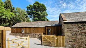 A rustic barn-style building with a gravel driveway and wooden gates.