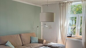 A living room with a beige sofa, a white coffee table, a floor lamp, and a window with curtains. - Cozy Scandinavian-style vacation home between the Schlei and the Baltic Sea (Rieseby)