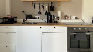 A modern kitchen with white cabinets, a wooden countertop, a built-in oven, and a hanging light fixture. - Cozy Scandinavian-style vacation home between the Schlei and the Baltic Sea (Rieseby)