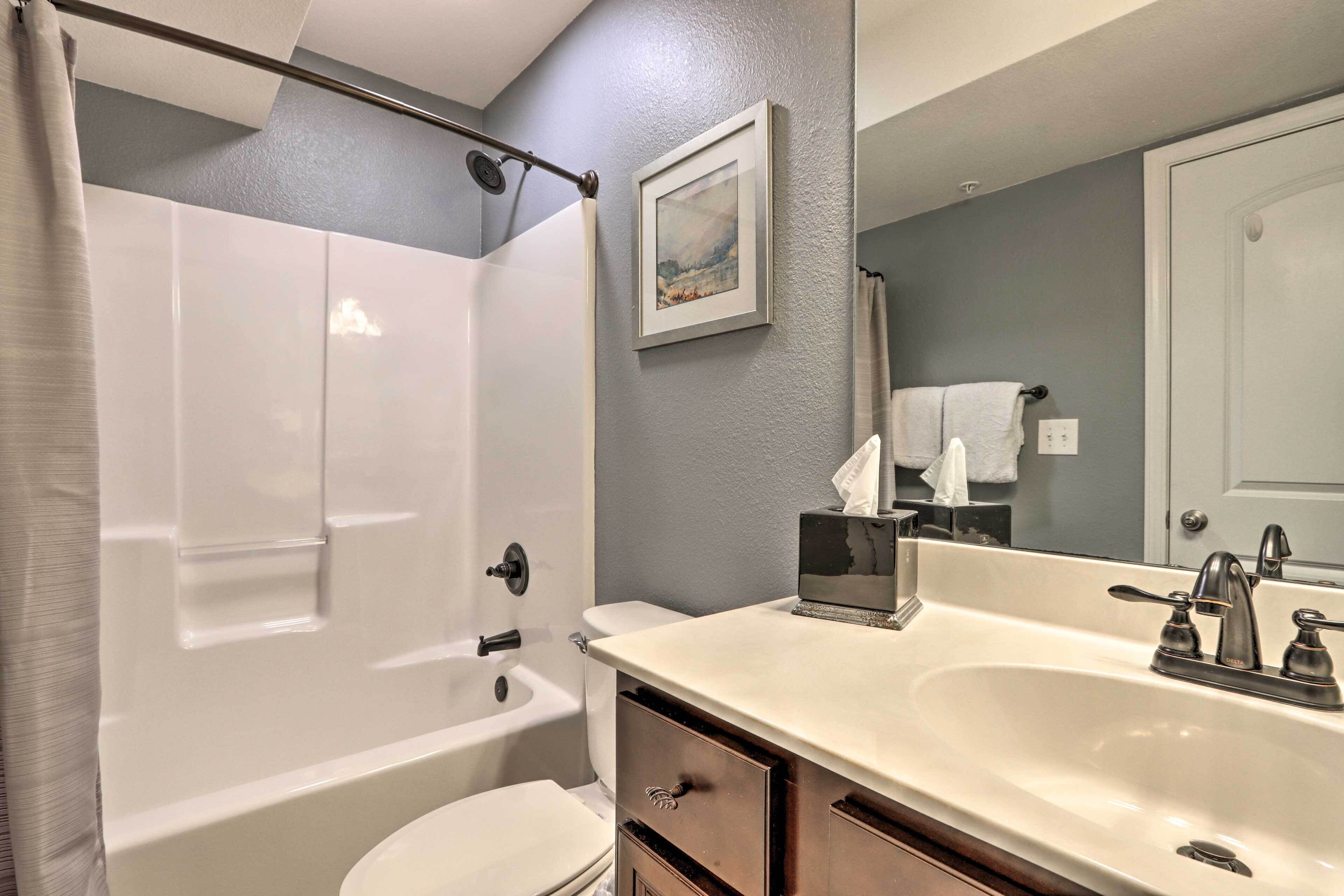A bathroom with a bathtub, toilet, sink, and a mirror.