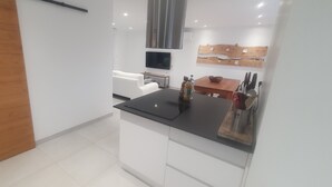 Een moderne keuken met witte kasten, een zwart aanrecht en een houten eettafel.