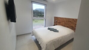 Een slaapkamer met een bed, een raam en een houten hoofdbord.