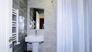 Une salle de bain avec un lavabo blanc, un miroir et un porte-serviettes.