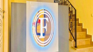 Un comptoir d’accueil avec un logo, un escalier et un mur jaune.