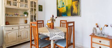 A dining area with a table, chairs, a cabinet, and a painting.