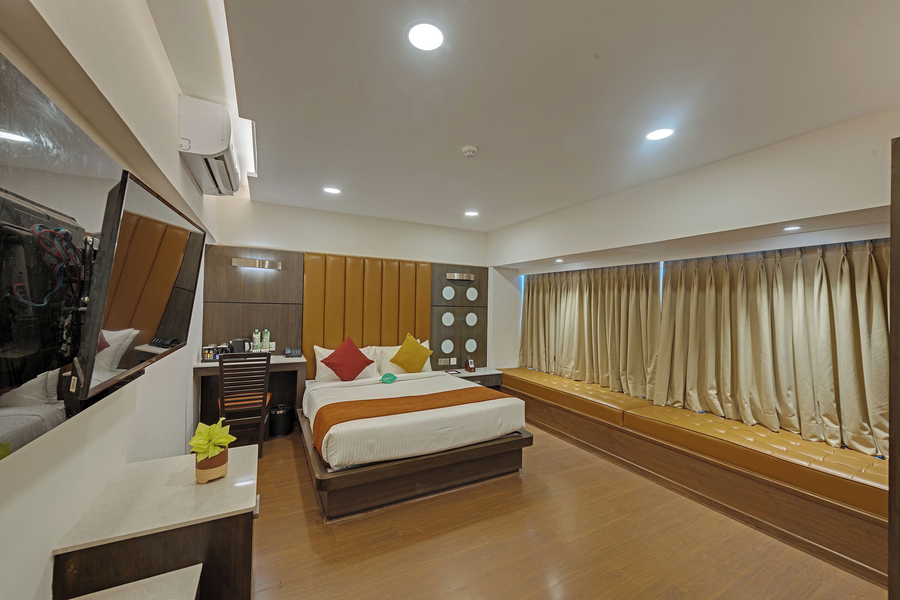 A hotel room with a bed, bedside table, mirror, dresser, and a view of the outside.
