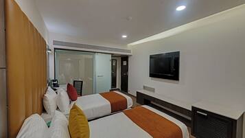 Habitación de hotel con dos camas, televisión y puerta corredera que da a un baño.