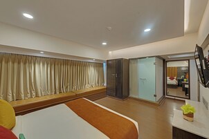 Hotelkamer met een bed, zithoek, kledingkast, badkamer en televisie.