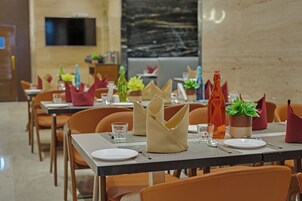 A dining area with tables set for service, chairs, and a television mounted on the wall.