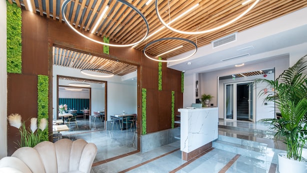 A modern lobby with a reception desk, seating area, and a staircase leading to an upper floor. - Campeador Inn (Cluj-Napoca)