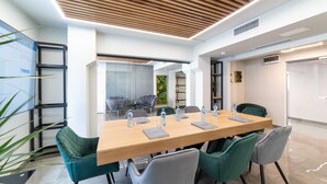 A modern meeting room with a wooden table, green and gray chairs, and a glass partition. - Campeador Inn (Cluj-Napoca)