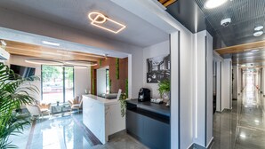 A modern reception area with a marble counter, seating, and a large window. - Campeador Inn (Cluj-Napoca)