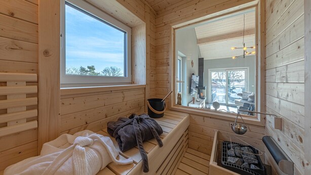 Un sauna en bois, équipé de bancs, d’un bain de sauna et d’un gril pour sauna.