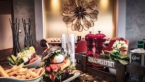 Un espace repas proposant une variété de plats, notamment des salades et des sandwichs, ainsi qu’un panneau indiquant « GENUSSHERKSTATT ».